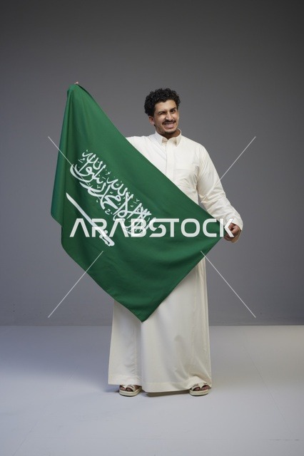 رجل سعودي يحمل علم المملكة العربية السعودية في الاستوديو