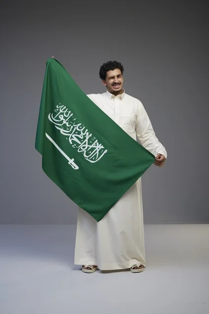 Saudi Man Holding Saudi Arabia Flag in Grey Studio Shot