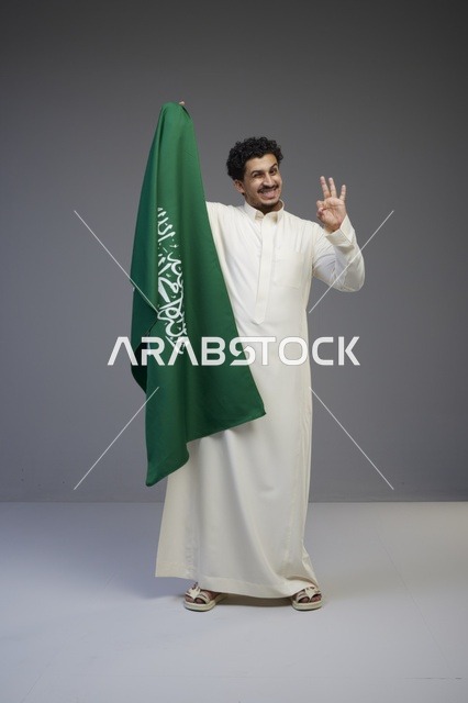 رجل سعودي يحمل العلم السعودي في الاستوديو