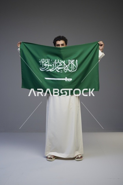 رجل سعودي يحمل علم المملكة العربية السعودية