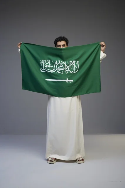 Saudi Man Holding Saudi Arabian Flag in Studio