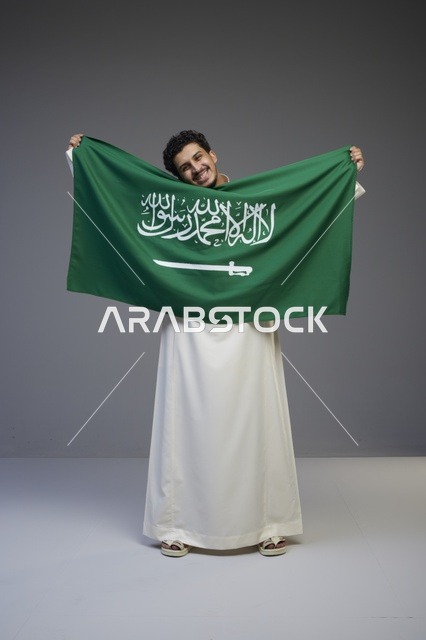 رجل سعودي يحمل العلم السعودي في الاستوديو