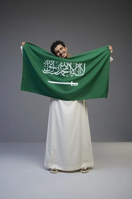 رجل سعودي يحمل العلم السعودي في الاستوديو