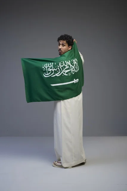 Saudi Man in Traditional Thobe Holding Saudi Arabia Flag