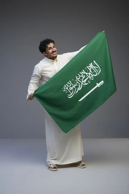 رجل سعودي يحمل العلم السعودي في الاستوديو