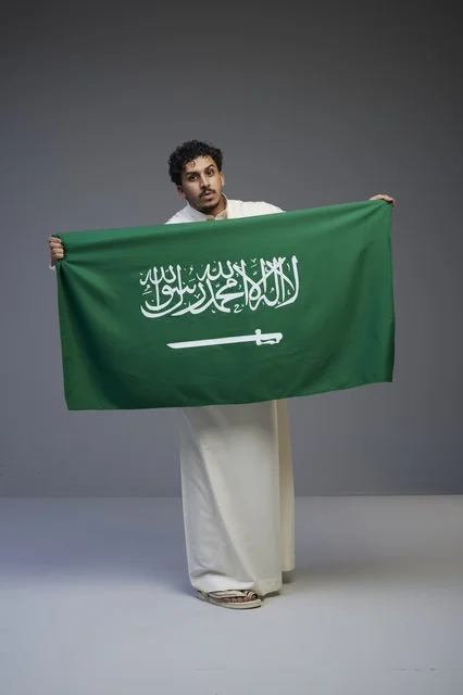 Saudi Man Holding National Flag in Studio Setting