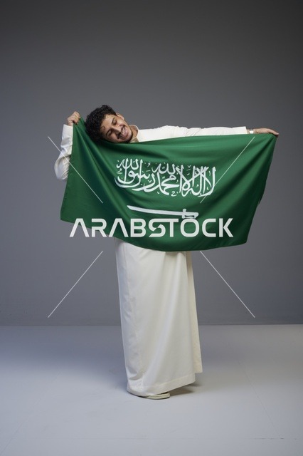 رجل سعودي يحمل علم المملكة العربية السعودية