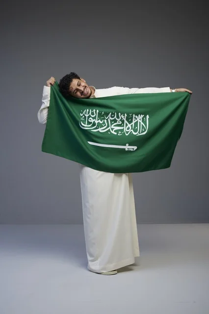 رجل سعودي يحمل علم المملكة العربية السعودية