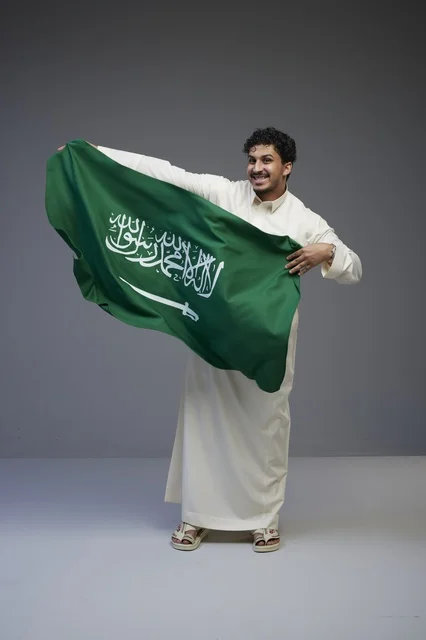 رجل سعودي يحمل علم المملكة العربية السعودية