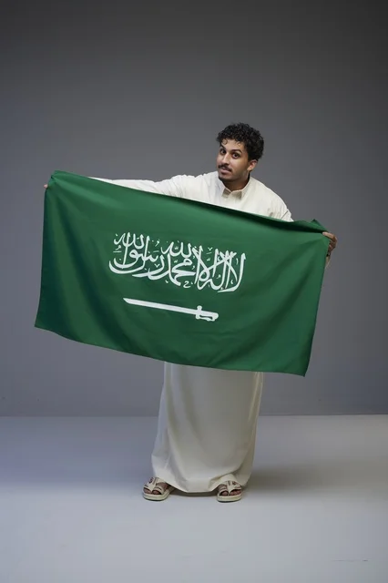رجل سعودي بالثوب التقليدي يحمل العلم السعودي