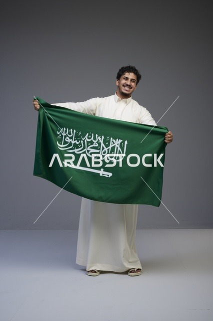 رجل سعودي يحمل علم المملكة العربية السعودية
