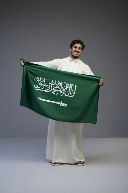 Saudi Man Holding Saudi Arabia Flag on Gray Background