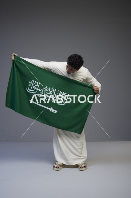 رجل سعودي يحمل العلم السعودي في الاستوديو