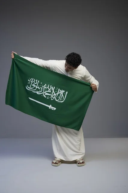 رجل سعودي يحمل العلم السعودي في الاستوديو