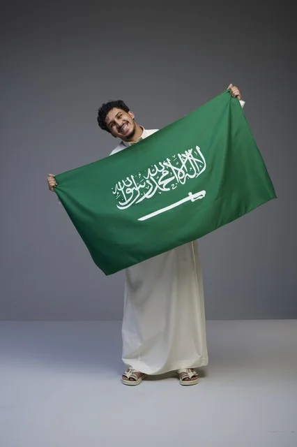 رجل سعودي يحمل العلم الوطني السعودي في الاستوديو