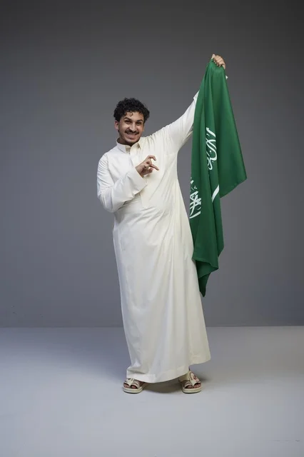 Smiling Saudi Man Holding National Flag in Studio Shot