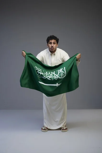 Saudi Man Holding National Flag in Studio Portrait