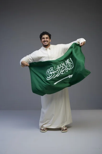 رجل سعودي يحمل علم السعودية في الاستوديو