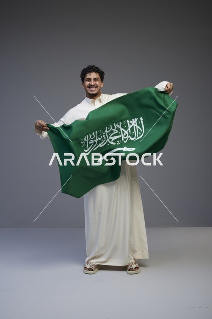 رجل سعودي يحمل علم المملكة العربية السعودية