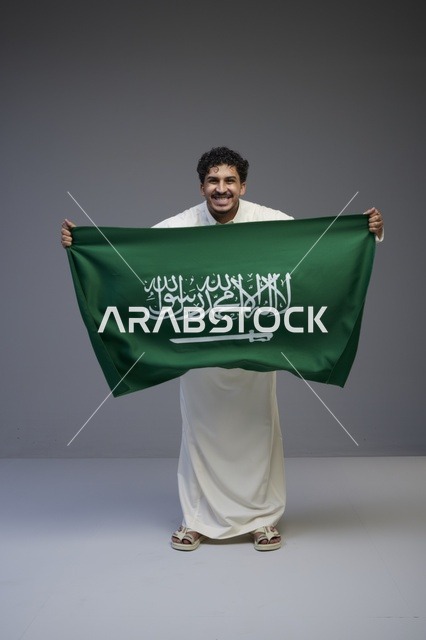 رجل سعودي يحمل علم المملكة في الاستديو