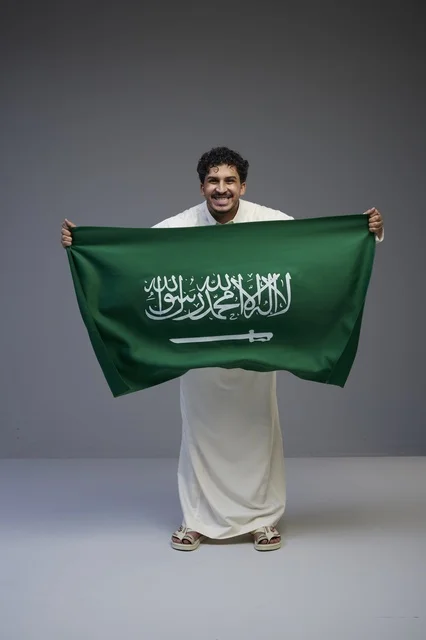 رجل سعودي يحمل علم المملكة في الاستديو