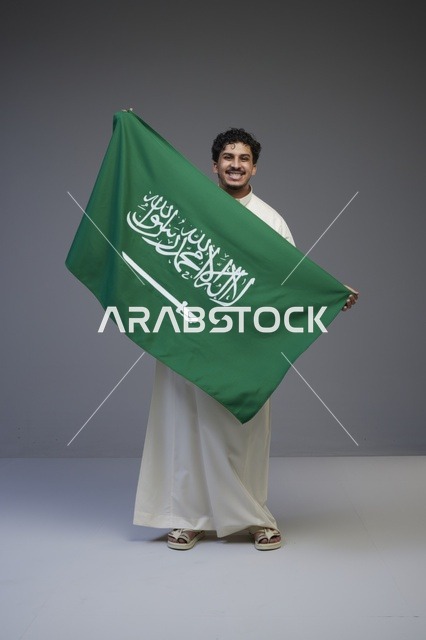 رجل سعودي يحمل علم المملكة العربية السعودية