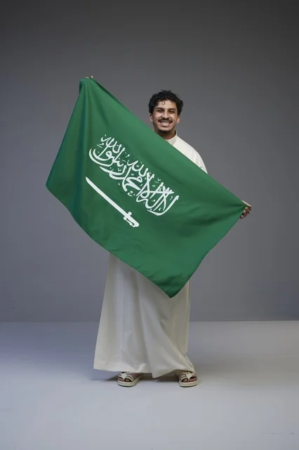 رجل سعودي يحمل علم المملكة العربية السعودية