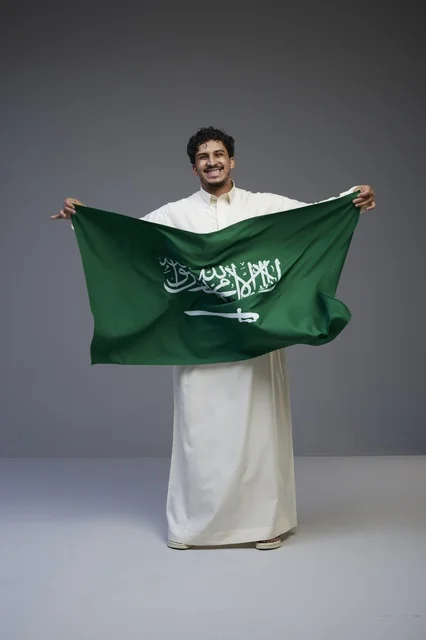 Saudi Man Holding Saudi Arabian Flag in Studio