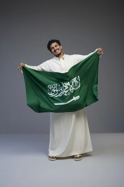 رجل سعودي يحمل علم المملكة العربية السعودية
