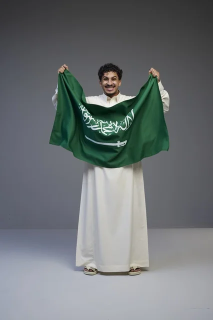 Saudi Man Holding Saudi Arabian Flag in Studio