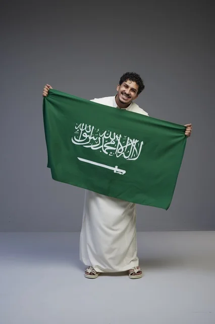رجل سعودي يحمل العلم الوطني السعودي في استوديو