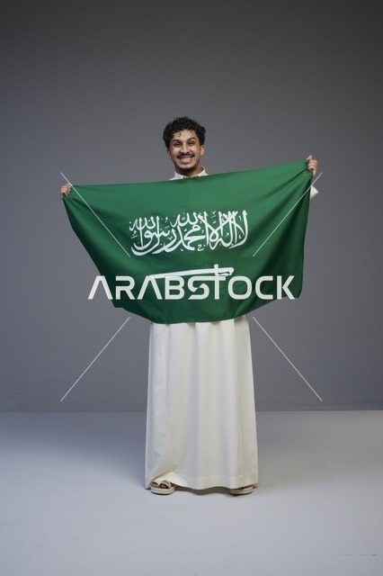 رجل سعودي يحمل علم المملكة العربية السعودية