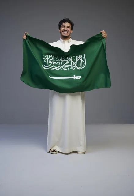 رجل سعودي يحمل علم المملكة في الاستوديو