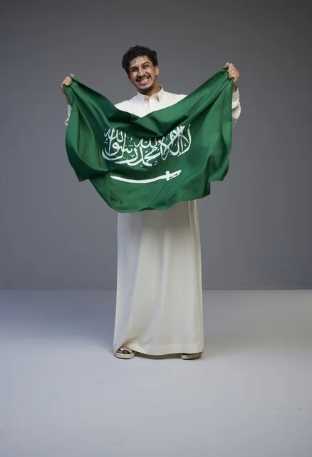 رجل سعودي يحمل علم المملكة العربية السعودية