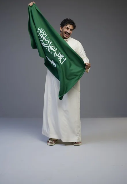 Saudi Man in Traditional Thobe Holding National Flag