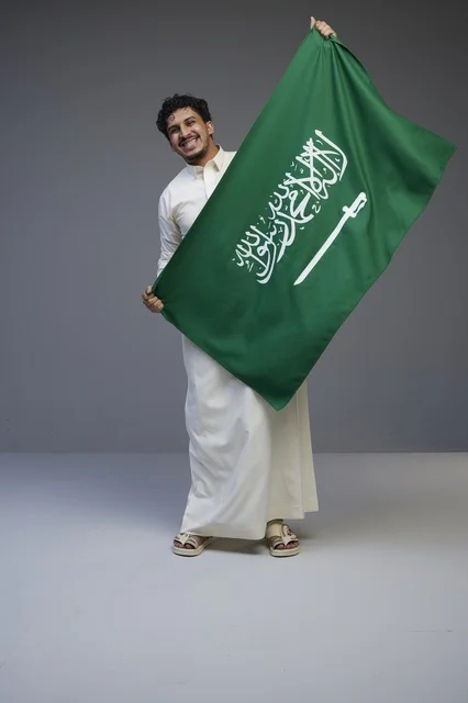 رجل سعودي يحمل العلم السعودي في الاستوديو