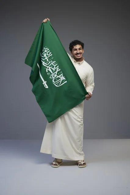 رجل سعودي يحمل العلم الوطني السعودي في الاستوديو