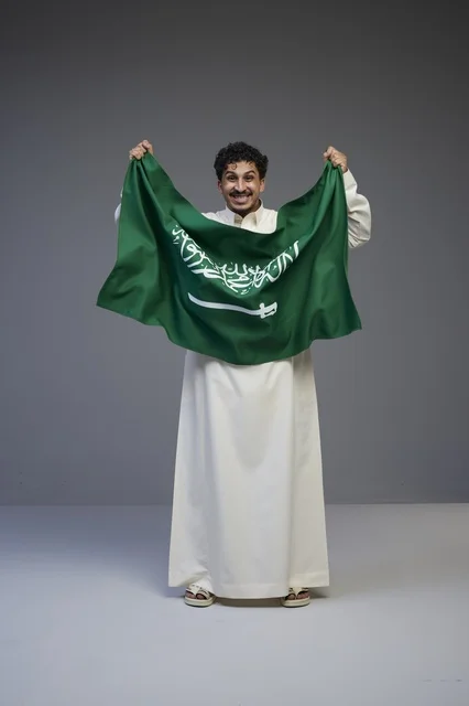 رجل سعودي يحمل علم المملكة العربية السعودية في استوديو
