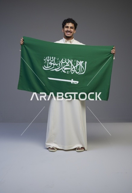 رجل سعودي يحمل علم المملكة العربية السعودية في استوديو