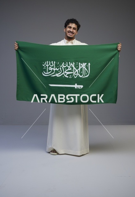 رجل سعودي يحمل علم المملكة العربية السعودية في الاستوديو