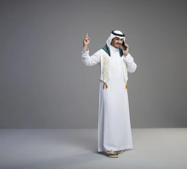 خريج سعودي يتحدث بالهاتف الذكي في الاستوديو