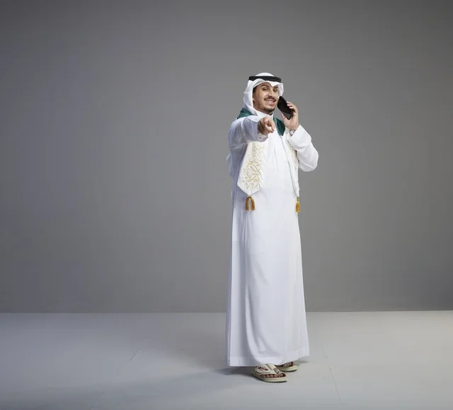 خريج سعودي يتحدث عبر الهاتف الذكي في استوديو رمادي