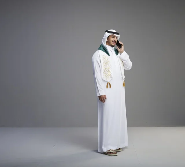 Saudi Graduate Talking on Smartphone Against Grey Backdrop
