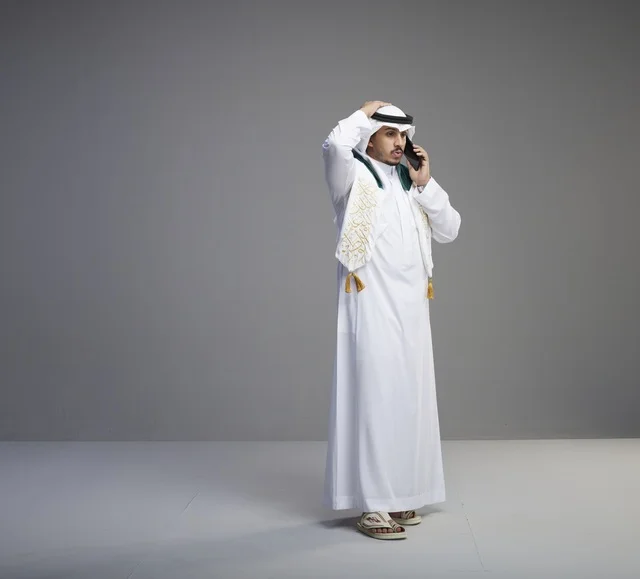 خريج سعودي بالثوب يتحدث عبر الهاتف الذكي