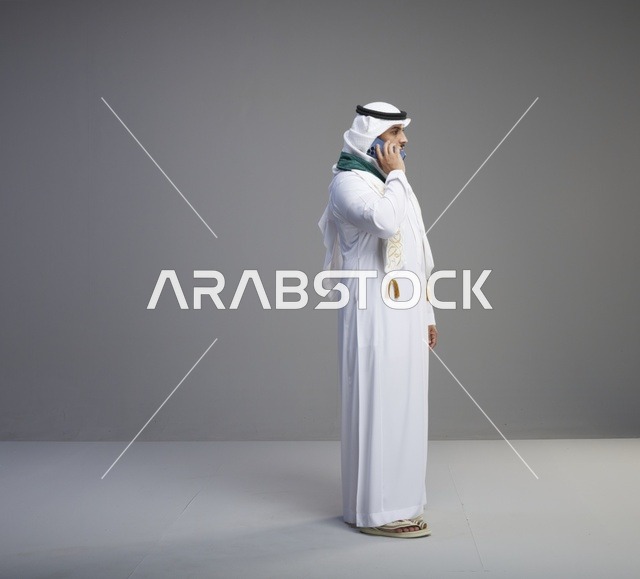 خريج سعودي يتحدث بالهاتف الذكي بخلفية رمادية