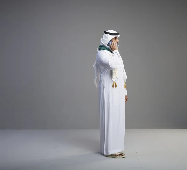 Saudi Graduate Using Smartphone on Grey Background