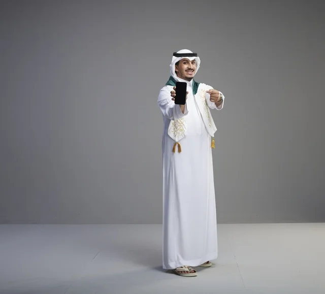 خريج سعودي يحمل هاتف ذكي بشاشة فارغة