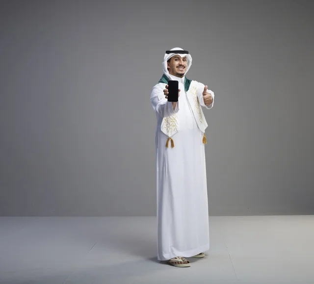 خريج سعودي يحمل هاتف ذكي مع إشارة النجاح