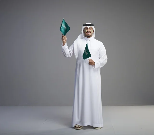 Smiling Saudi Man Holding National Flags in Studio