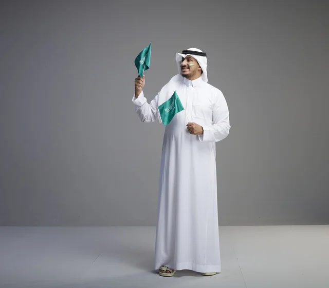 Smiling Saudi Man Holding Two National Flags